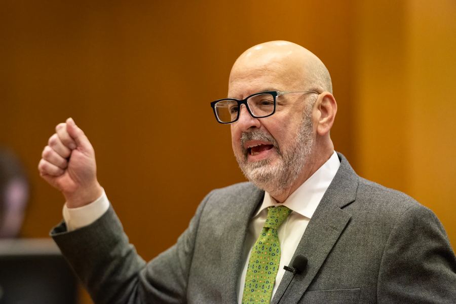 Douglas Weinstein gesturing while addressing the court in a gray suit and green tie